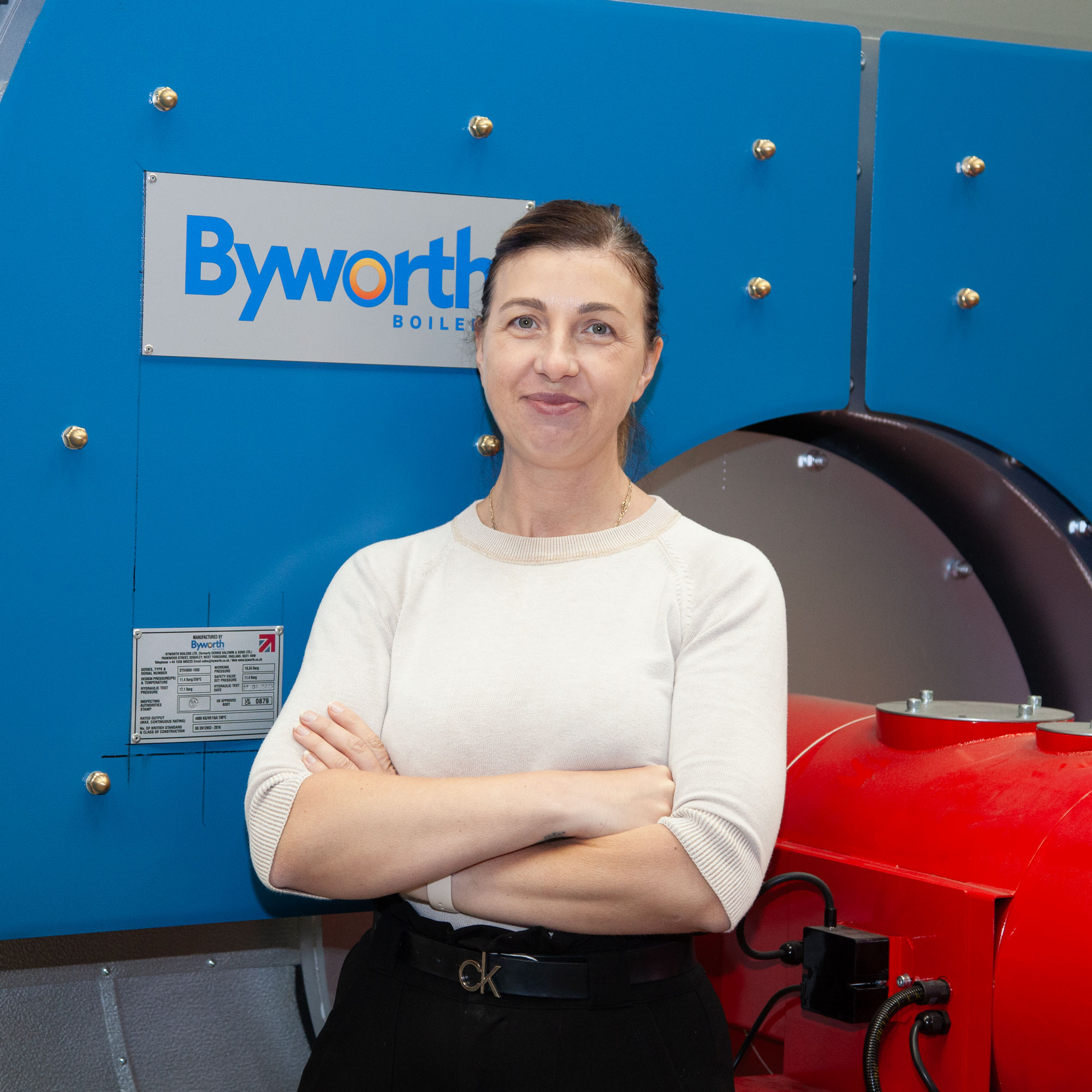 Lady smiling for the camera in front of a boiler 